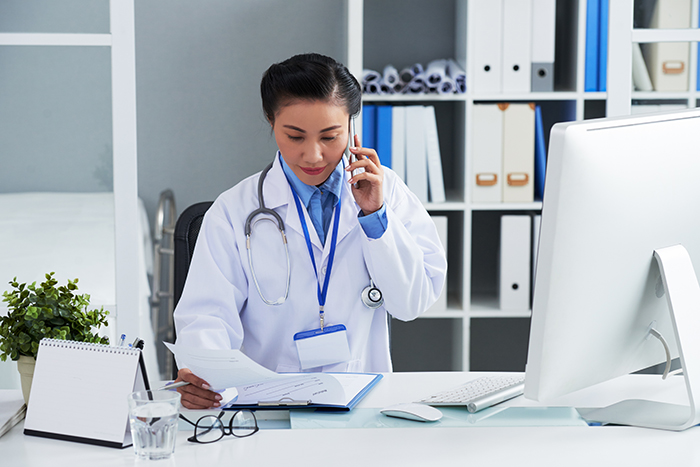 Médica em um consultório falando ao telefone